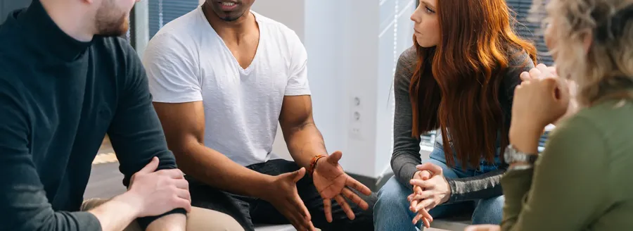 A group therapy session in progress, participants seated in a circle talking.