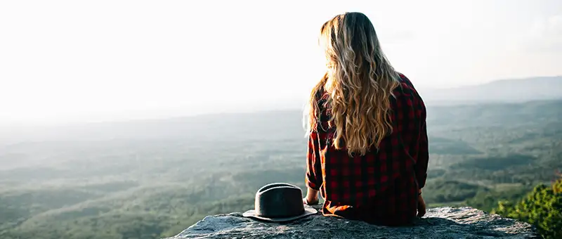 woman sits on a cliff